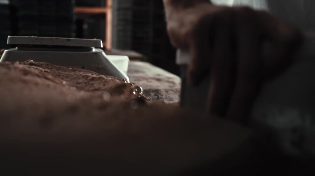 Male baker manually divides large mass of dough into blanks using scraper for scaling phase in private bakery kitchen. Production of bread and pastries. Baking ingredients preparation. Slow motion x4