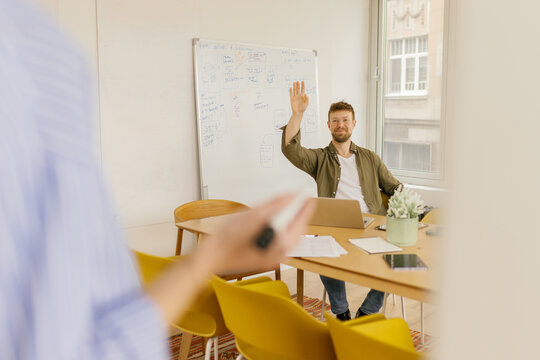 A man raises his hand during a presentation in the office
