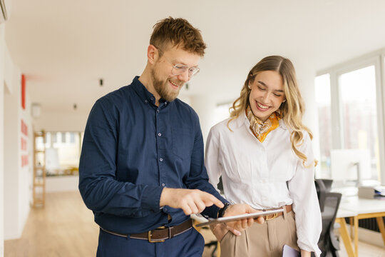 Smiling colleagues discuss financial plans on a digital tablet