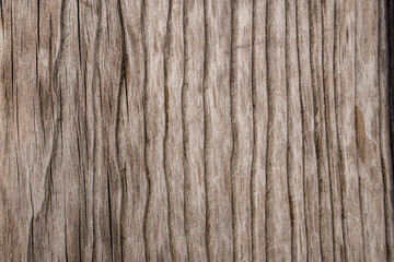 Fototapeta premium Close-up weathered wood surface with natural vertical grain and muted brown tones, providing a rustic neutral texture for backgrounds, branding, packaging, and design projects.