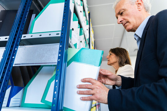 Businessman and businesswoman search for a document in the archive