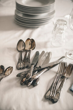 Table with stack of plates, water glasses and silver cutlery