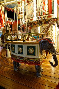 Ornate vintage carousel featuring an elephant and painted horses under warm amusement-park lights, offering a nostalgic visual for travel, entertainment, and family content.