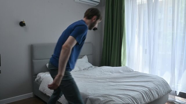 Man making his bed, putting a white duvet on it after waking up