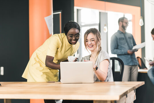 Smiling colleagues working on laptop in office