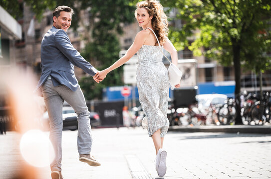 Happy carefree couple running in the city