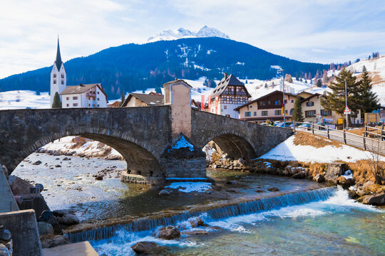 A stone bridge crosses river Julia in winter resort Savognin