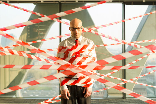 Businessman tangled in barrier tape