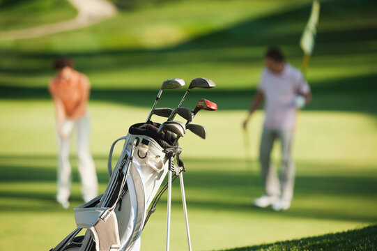 Golf bag and club with man and woman playing on course in Italy