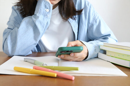 勉強に集中できずスマホを見る女性
