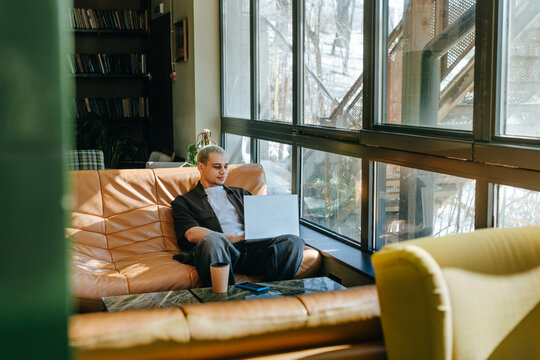 A businessman works on his laptop on a sofa in a coworking space