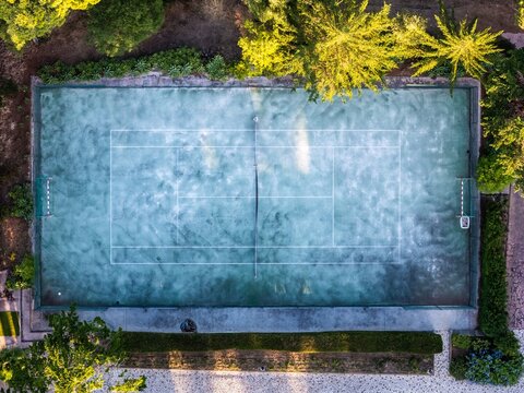 Aerial view of a tennis court at Quinta da Marinha surrounded by lush trees and greenery in Cascais, Lisbon, Portugal.