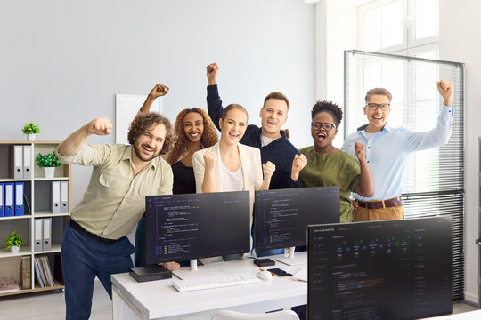 Developers team celebrate success in office. Programmers and coders cheer by monitors as startup hits milestone, showing teamwork, victory and celebration. Clear concept of teamwork success.
