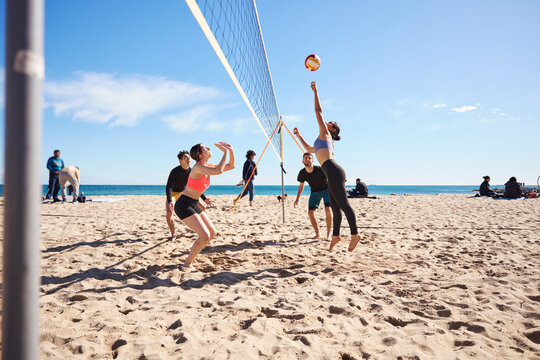 Group of young athletes playing volleyball while taking part in a recreational game by the beach