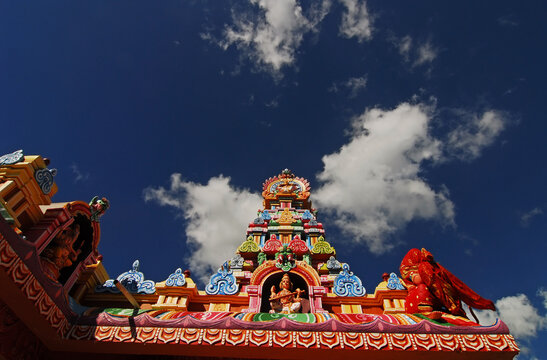 Mauritius, Bambou, low angle view of colorful spire of a Hindu temple with the figurines of Hindu god against cloudy sky