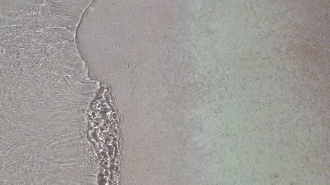 Waves crashing on sandy beach during daylight hours 