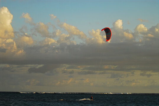 Mauritius, Le Morne, paraglider with parachute in the middle of a sea against cloudy sky at dusk