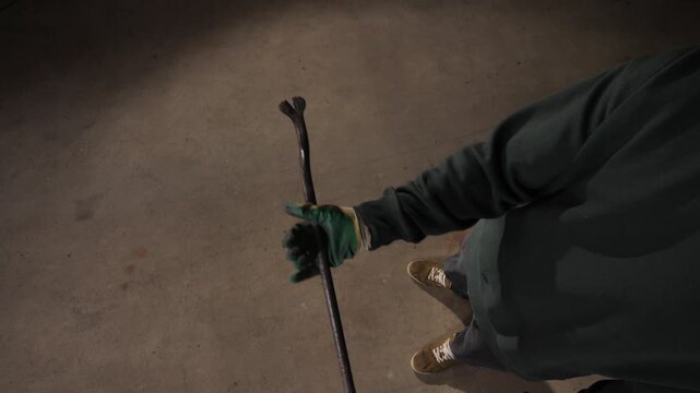 High angle view gloved hand holding a metal crowbar over a concrete floor, conveying concepts of burglary, crime, and breaking and entering