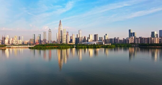 Aerial view of the modern urban skyline of Shenzhen, China reflected in the calm lake water at Talent Park in the morning