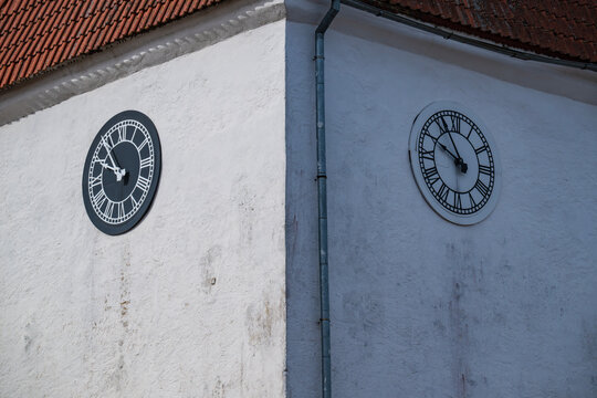 Black and white tower clocks with Roman numerals on the historic Lutheran church wall in Talsi, Latvia.