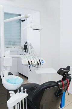 Dental equipment and chair in stomatology for treatment unit with professional dental handpieces, air water syringe, control panel, tubing and precision instruments arranged on modern dental chair ver