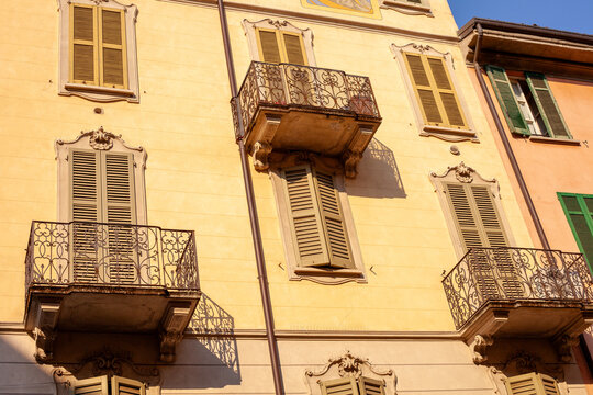 Yellow Historic Building Facade with Wrought Iron Balconies and Shutters Como Italy.