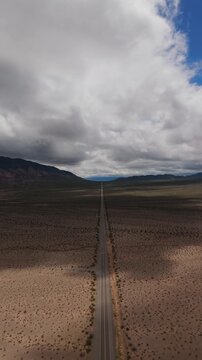 Long aerial expanse horizon of Recta del Tin Tin crossing desert plain beneath dramatic clouds, drone vertical