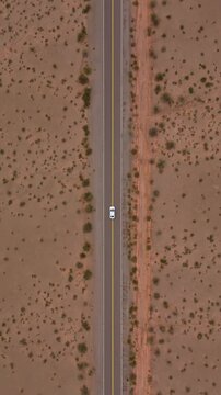 Top down aerial tracking of car driving Recta del Tin Tin through arid landscape, drone vertical