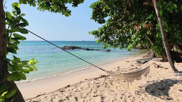 Tropical hammock on Batu Topeng Beach, Karimunjawa Island with stunning blue sea view, perfect for travel, tourism, vacation and paradise destination concepts.