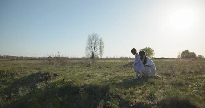 Young mother with child daughter spend time playing enjoying nature. 4K 10-bit