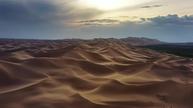 Aerial view of Gobi Desert dunes under a dramatic sunset sky in Nomgon, Omnogovi, Mongolia.