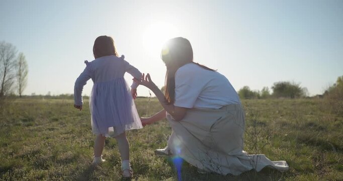 Young mother with child daughter spend time playing enjoying nature. 4K 10-bit