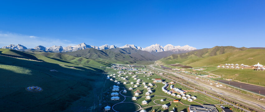 Aerial view of Maya Snow Mountain and Tibetan Tent Resort Camp on Alpine Grassland, Gansu, China.