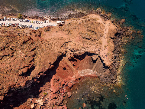 Birds eye top down aerial drone shot of red volcanic rocks and crystal clear water at Red Beach Santorini