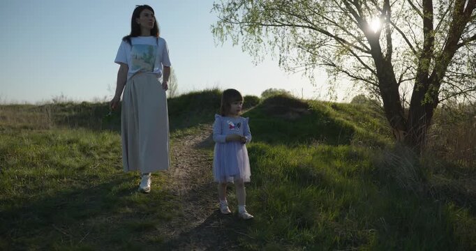 Young mother with child daughter spend time playing enjoying nature. 4K 10-bit