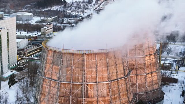 Aerial view of cooling towers at a power plant in winter industrial landscape generating steam and thermal energy.