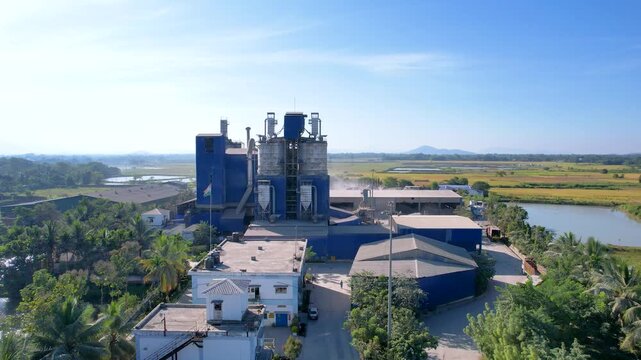 Drone ascending industrial cement factory complex revealing rural