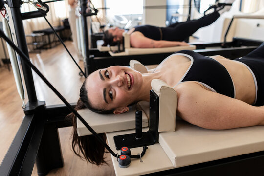 Smiling woman enjoying pilates reformer workout in studio