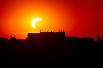 Partial solar eclipse sbove a city building   Częściowe zaćmienie słońca nad budynkiem miejskim © Adrian White