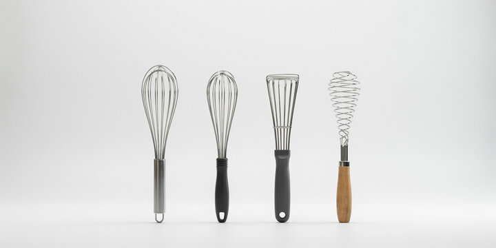Four different kitchen whisks with various handles and wire shapes on white surface