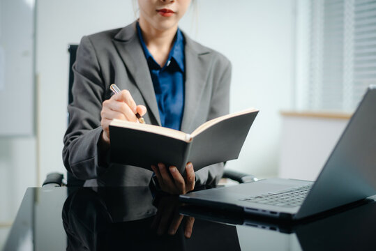 Close-up view of young professional businesswoman writing his idea concepts on notebook while working on his project at office