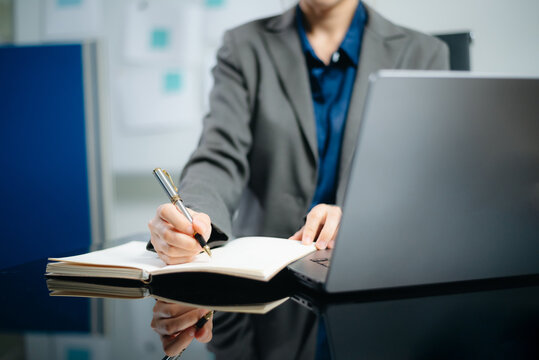 Close-up view of young professional businesswoman writing his idea concepts on notebook while working on his project at office