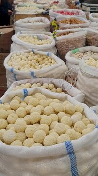Bags of traditional kurut, dried fermented dairy balls, displayed for sale at a local market. Vertical footage showing a traditional Central Asian food product and local market culture.