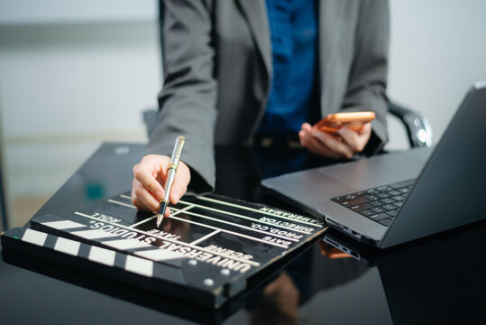 Creative filmmaker planning a video production project with a clapperboard, laptop and smartphone, representing filmmaking, content creation, media and digital storytelling.