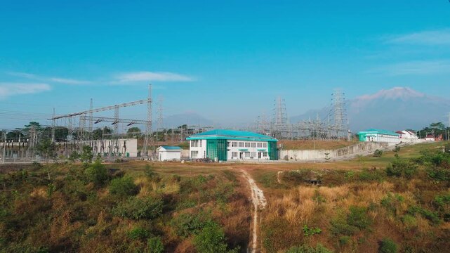 Aerial view of Ampel 150kV Substation with Mount Merbabu and Mount Merapi in the background, surrounded by electrical infrastructure and rural landscape in Kecamatan Ampel, Jawa Tengah, Indonesia.