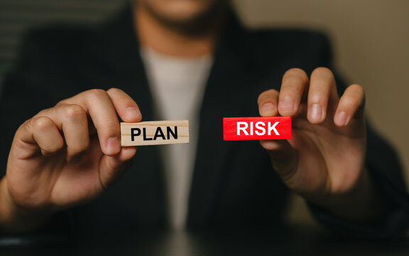 Businessman Holding Wooden Blocks with Risk and Plan Words for Strategy Concept