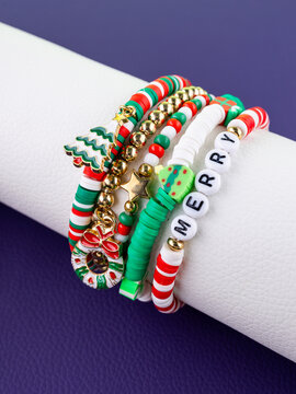 Close-up of a set of red and green Christmas bracelets with pendants in the shape of a Christmas tree, a holiday wreath, and Santa Claus