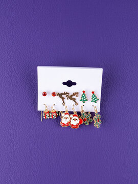 Close-up of a set of Christmas earrings featuring reindeer, snowflakes, Santa Claus, and other festive designs