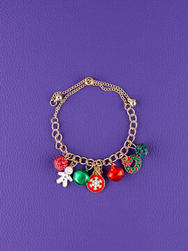 Close-up of a metallic Christmas bracelet with pendants shaped like a snowflake, holiday wreath, bells, and other festive charms.