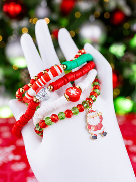 Close-up of a set of red and green Christmas bracelets with pendants featuring Santa Claus, reindeer, and a Christmas tree